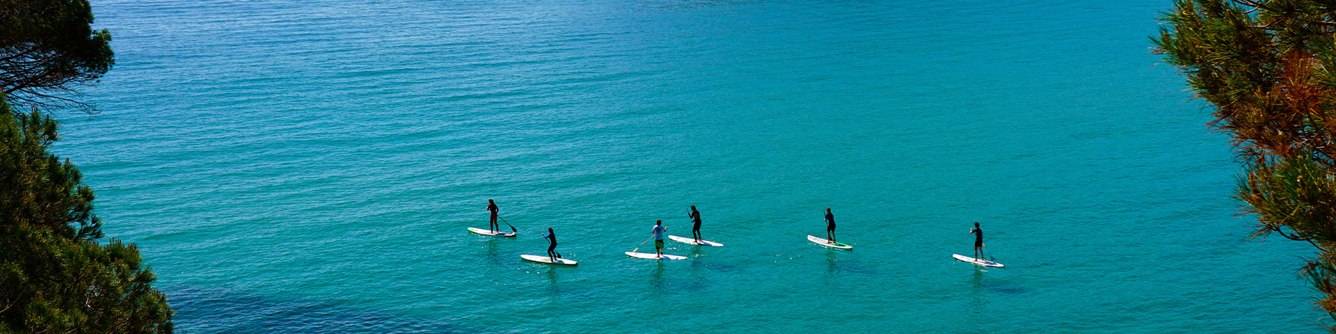 Un grupo practica paddle surf en las aguas de Palamós, en la Costa Brava gerundense