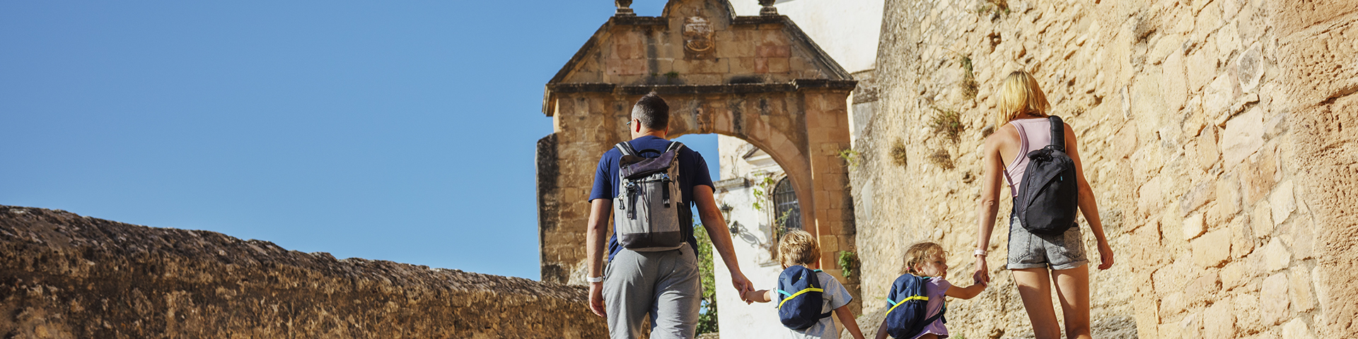 Una familia recorre las calles históricas de Ronda camino del Arco de Felipe V, uno de los rincones monumentales de la ciudad malagueña.