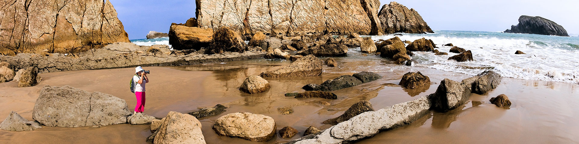 Photographer capturing the imposing rock formations of La Arnía beach (Costa Quebrada, Cantabria)