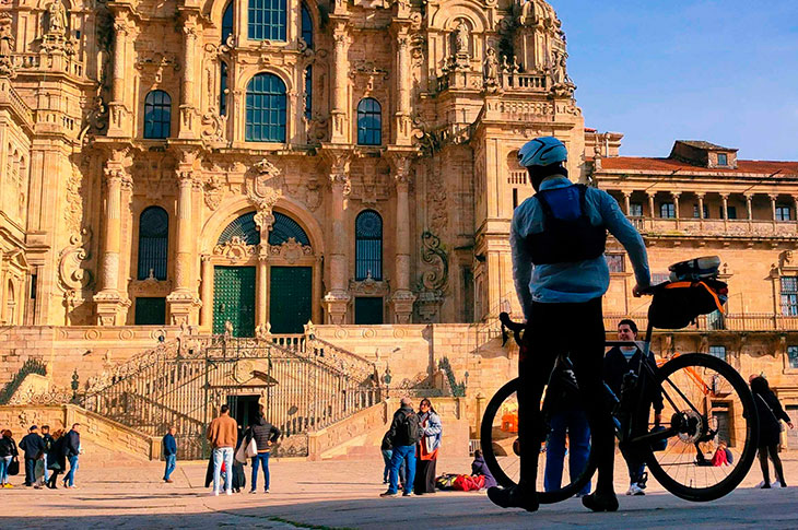 Joven en bicicleta terminando su peregrinaje en la entrada principal del Obradoiro, Catedral de Santiago de Compostela, España Joven en bicicleta terminando su peregrinaje en la entrada principal del Obradoiro, Catedral de Santiago de Compostela, España