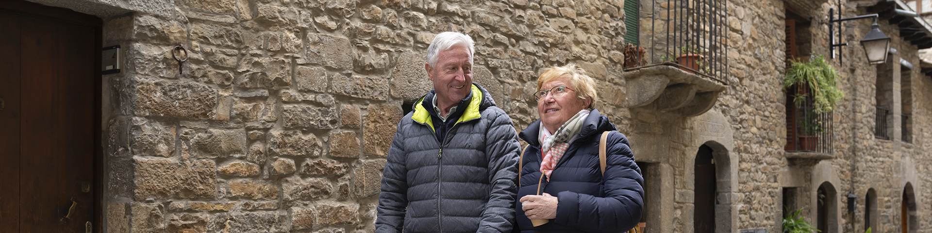 Pareja sénior por las calles empedradas del casco histórico de Aínsa, uno de los pueblos más emblemáticos del Pirineo aragonés.