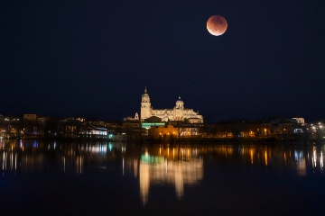 Måneformørkelse i havneområdet i Salamanca med katedralen, der oplyser floden Tormes. Castilla y León