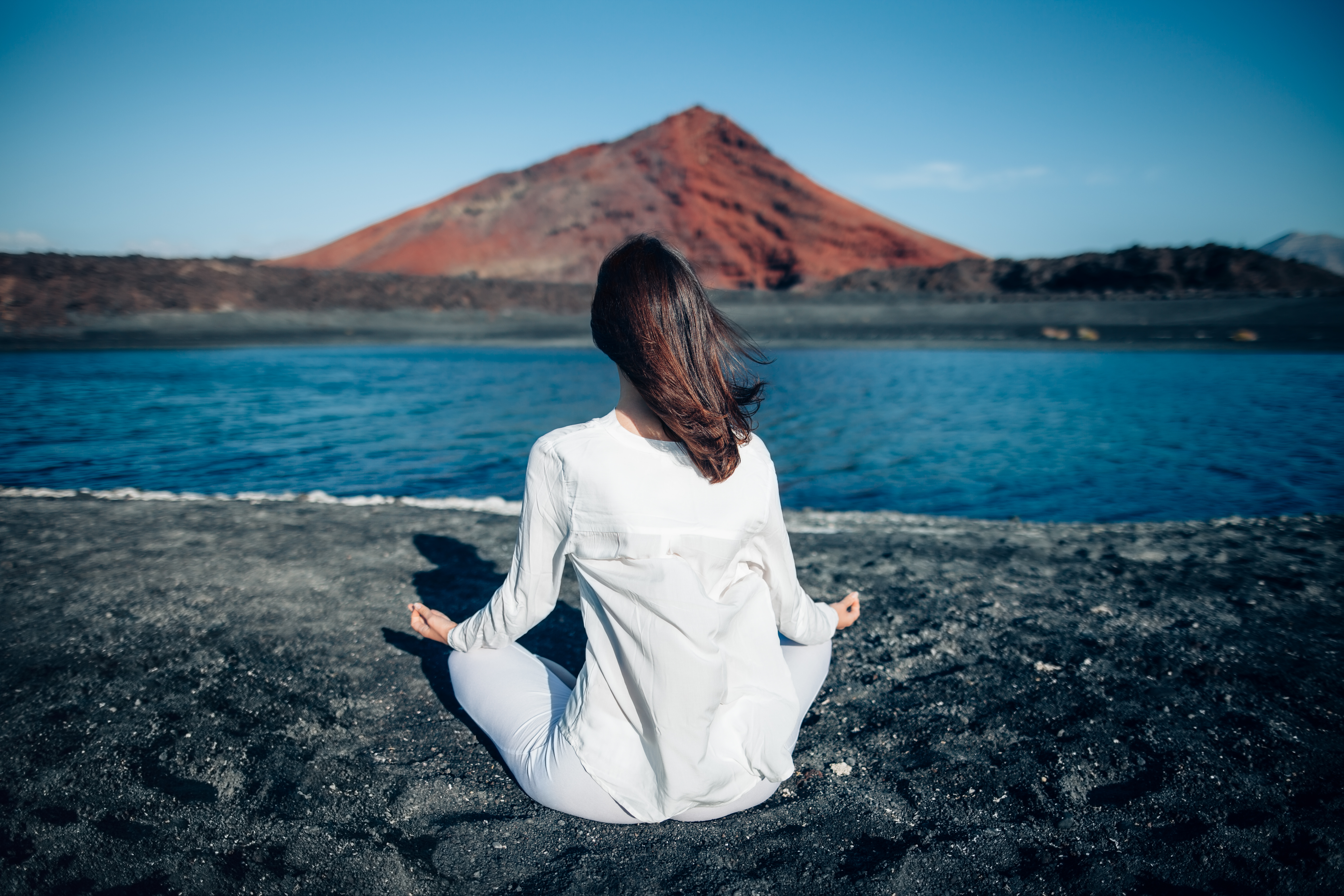 As Ilhas Canárias são estabelecidas como um dos destinos favoritos dos amantes de yoga. Na imagem, jovem a meditar na Playa Bermeja, Lanzarote