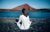 As Ilhas Canárias são estabelecidas como um dos destinos favoritos dos amantes de yoga. Na imagem, jovem a meditar na Playa Bermeja, Lanzarote As Ilhas Canárias são estabelecidas como um dos destinos favoritos dos amantes de yoga. Na imagem, jovem a meditar na Playa Bermeja, Lanzarote